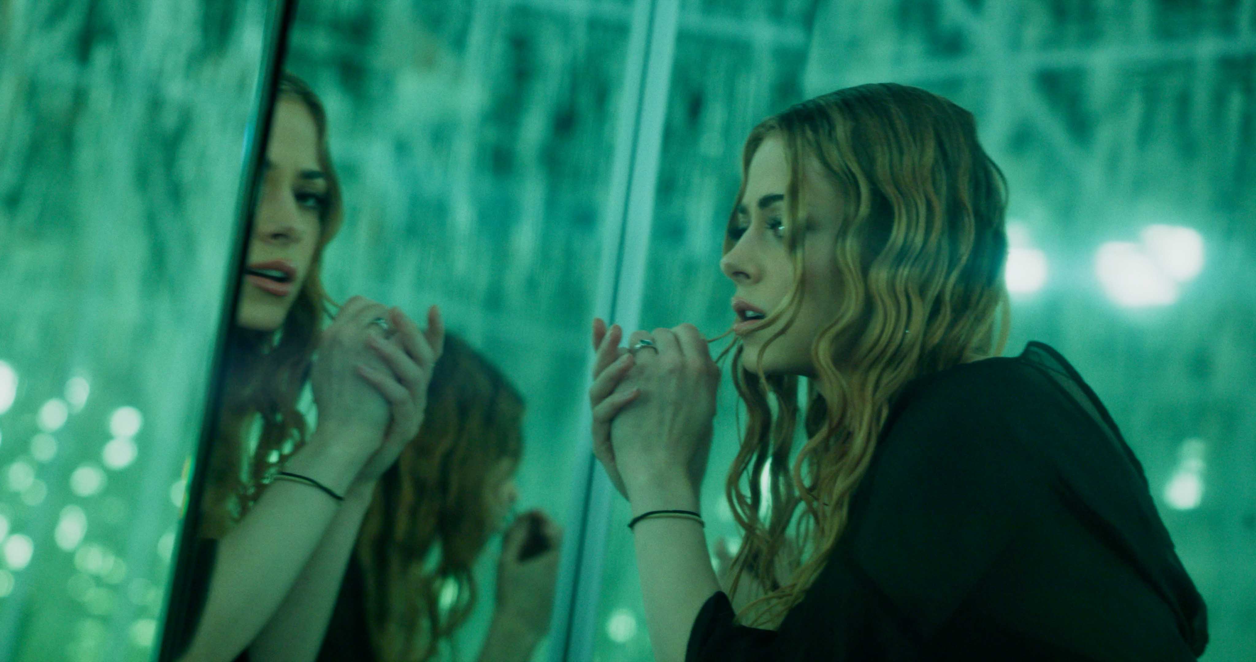 Front-facing Porsche GT3 with headlights on, carving through a chicane at twilight in alpine scenery.